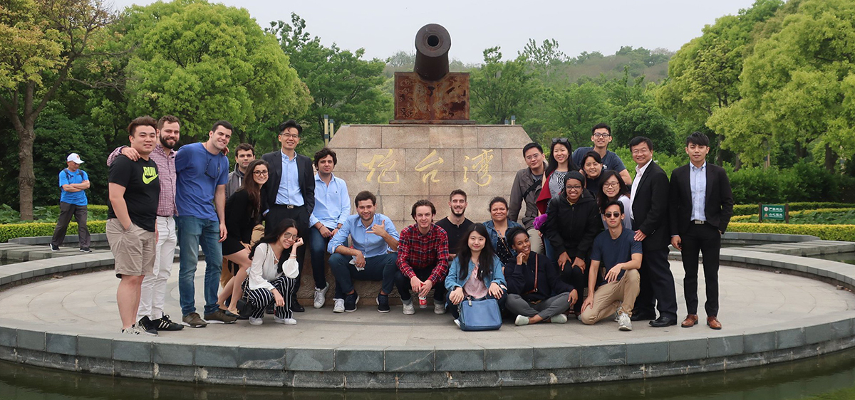 A group of students standing near a war monument of a cannon in a foreign country.